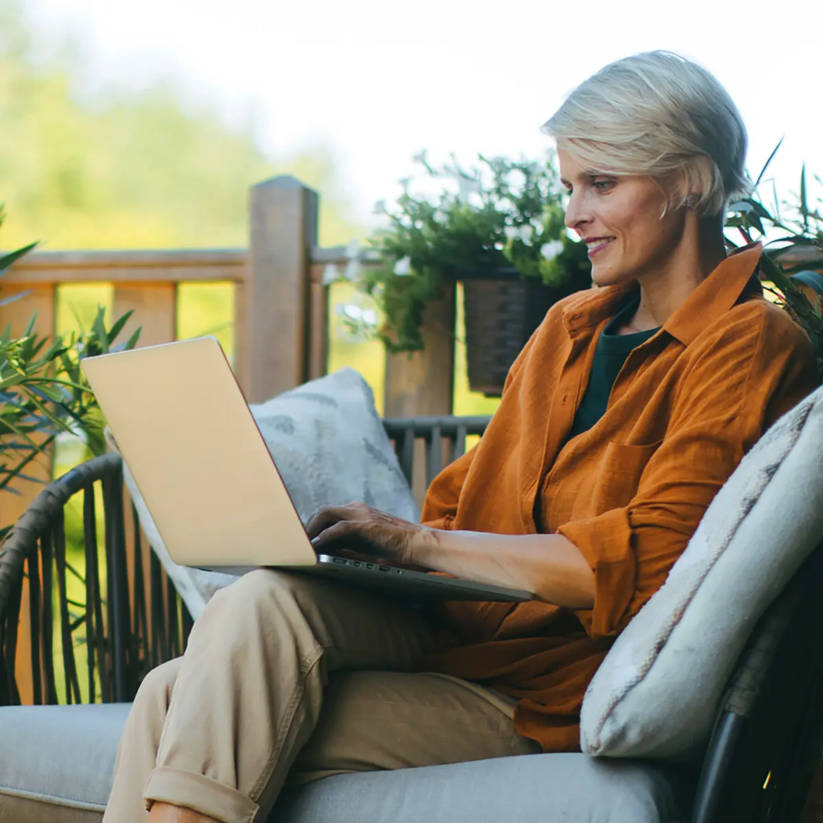 Frau arbeitet entspannt mit Laptop auf der Terrasse